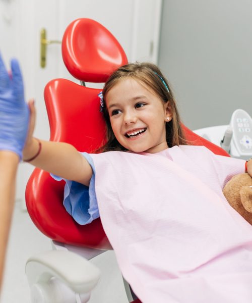 Cute little girl sitting on dental chair and having dental treatment.